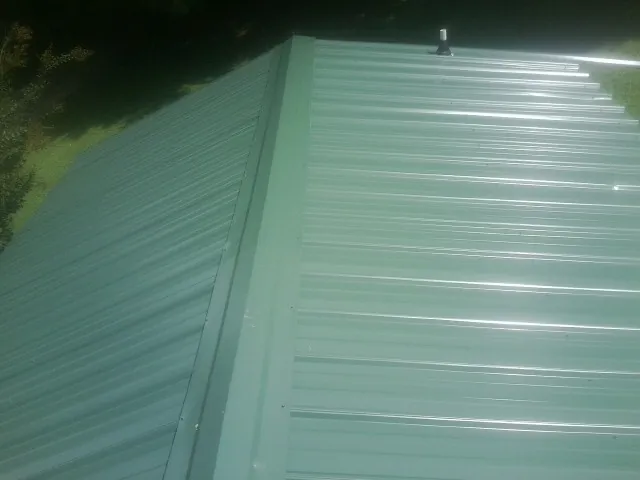 New green metal panels meeting at the ridge of a roof — Flat Roof Repair work by our crew in Palm