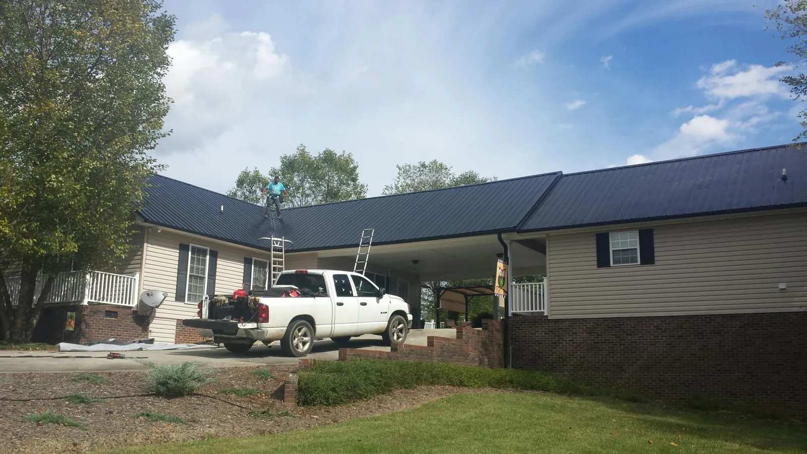 Black metal roof over a home and attached breezeway with ladders set in Palm