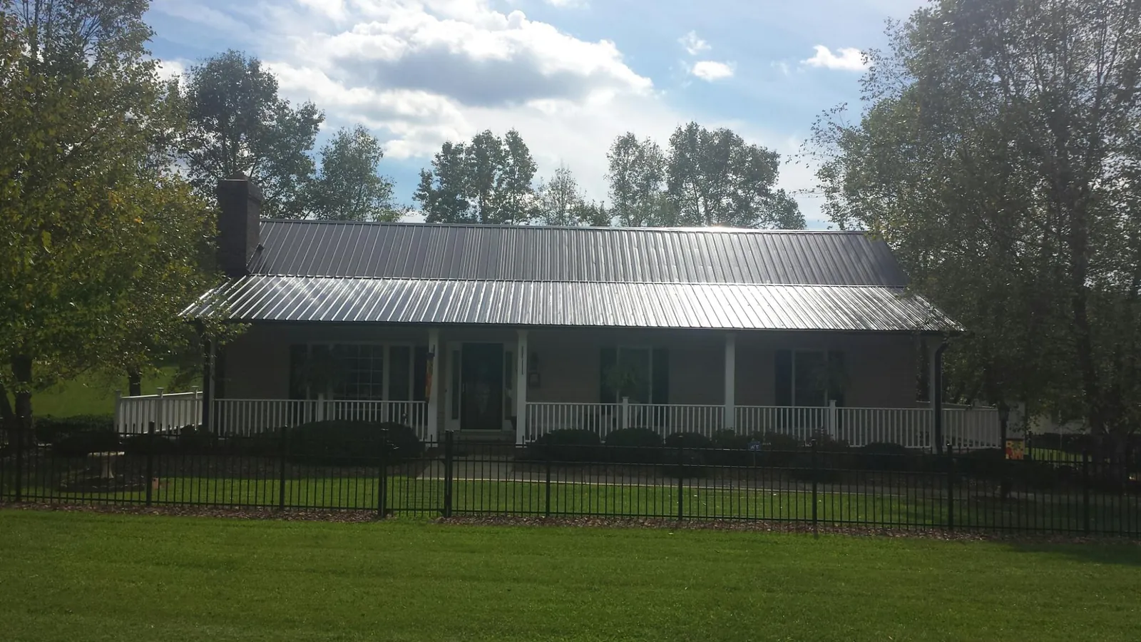 Gray metal roof on a brick ranch with a full width front porch — Gutter Guard Installation work by our crew in Palm