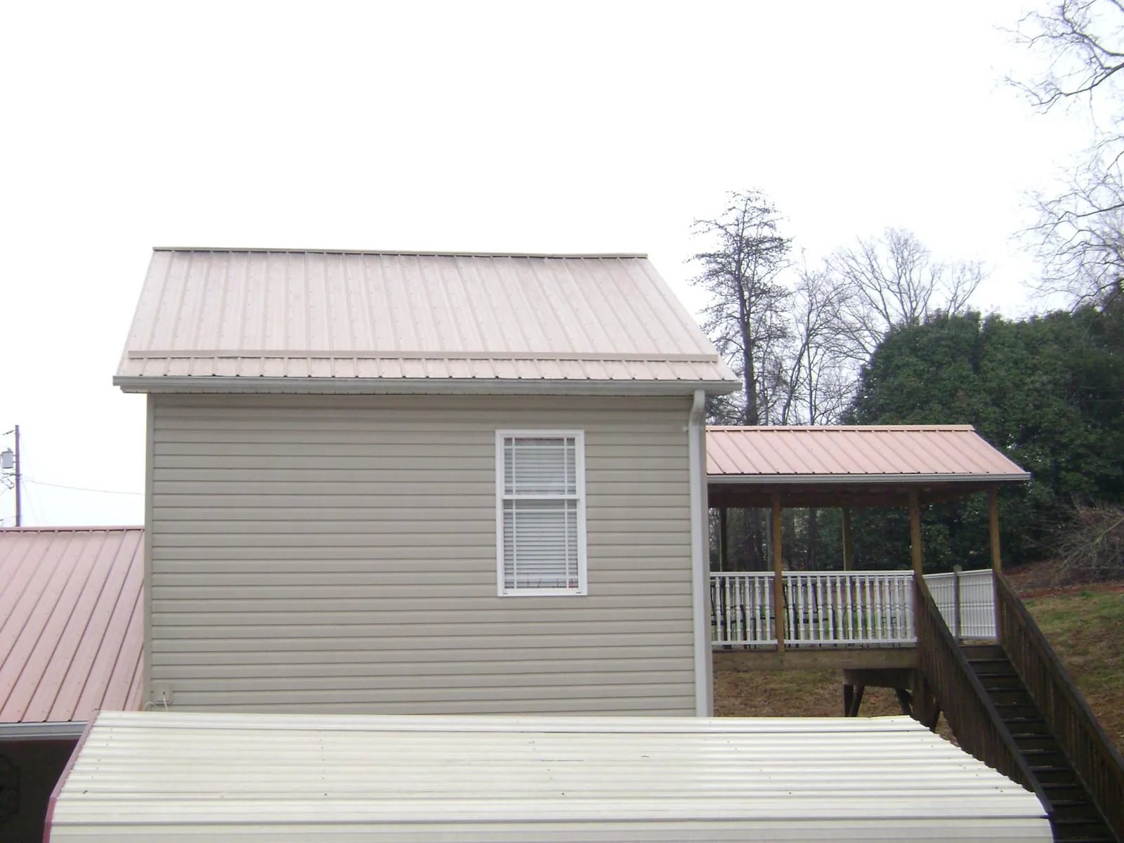 Tan metal roofs on a two story addition and attached porch, from a Roof Replacement job in Palm