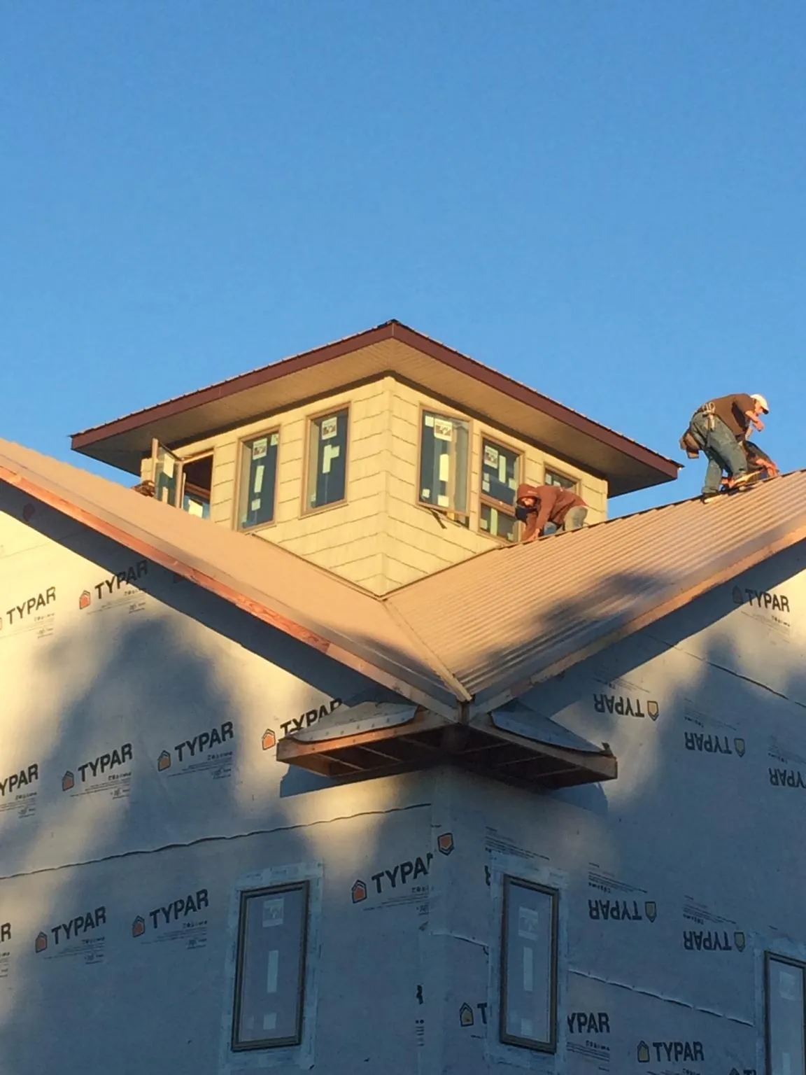 Roofers working around a rooftop cupola on a new metal roof at sunset — Roof Waterproofing in Palm by Roofing Brothers